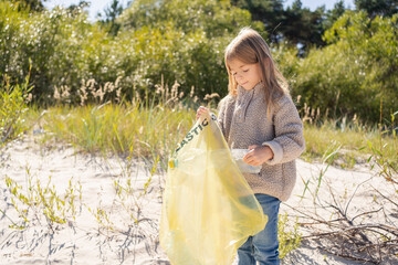 Wall Mural - Save environment concept, a little girl collecting garbage and plastic bottles on the beach to dumped into the trash