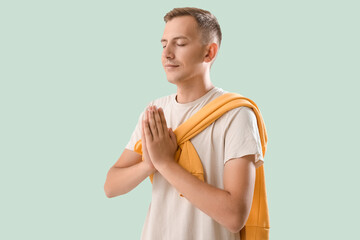 Poster - Young man meditating on green background