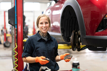 Wall Mural - Handsome mechanic job woman in uniform working on car