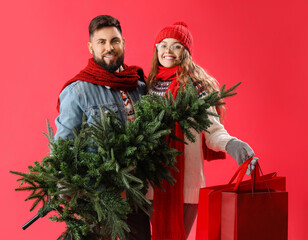 Sticker - Young couple with Christmas tree and shopping bags on red background