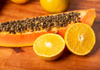 Wall Mural - Papaya and oranges, scene with sliced ​​papaya and oranges over rustic wood, selective focus.