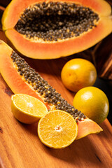 Wall Mural - Papaya and oranges, scene with sliced ​​papaya and oranges over rustic wood, selective focus.