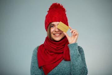 Smiling woman in winter clothes holding credit card. Advertising female studio portrait.