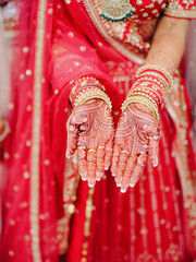 Wall Mural - Above view of woman`s hand with henna drawings with ornamentals, dressed in red traditional wedding dress and gold jewelry