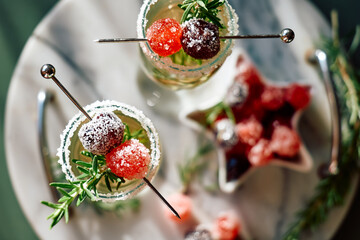 Christmas cocktail with sparkling wine, rosemary and cherry. Winter xmas and new year holidays champagne drink, top view.