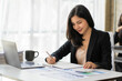 © ArLawKa - Asian businesswoman working on finance and business information at the officeYoung people are analyzing plans using data from paper graphs.
