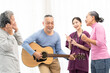 © Wongsakorn - Group of senior people enjoying with activities together with doctor. Elderly people having fun concept. Happy senior playing guitar and singing songs having fun together.