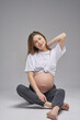 © Евгений Бордовский - Young beautiful pregnant girl on a white background. A young mother smiles beautifully and enjoys pregnancy. Studio photo.