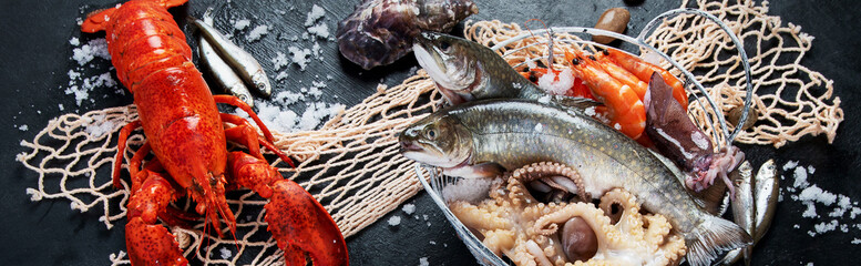 Poster - Fresh fish and seafood assortment on black background, fish market. Healthy diet eating concept. Top view. Panorama, banner