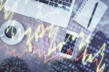 Double exposure of financial chart hologram over desktop with phone. Top view. Mobile trade platform concept.