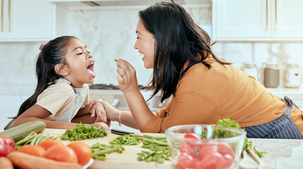 Wall Mural - Health, eating and food with mother cooking in kitchen with nutrition, vegetables and care. Home, lunch and healthy diet of asian family with young daughter tasting green veggies with mom.