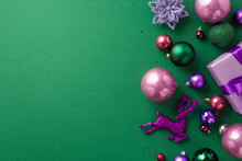 Christmas Decorations Concept. Top View Photo Of Lilac Giftbox Pink Violet Green Baubles Reindeer Flower Ornaments And Confetti On Isolated Green Background With Blank Space