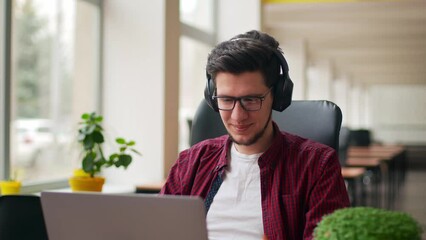 Developer, video editor man in headphones working with laptop at spacious coworking alone enjoying music. Stylish creative musician producer listens song in office alone. Online gamer playing games.