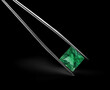 Square Emerald Gemstone in Tweezers on Black Background