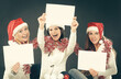 © yurolaitsalbert - three young girls in costume of Santa Claus showing blank sheets