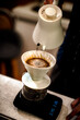 Barista making a Geisha coffee, pouring hot water from kettle over a ground coffee powder