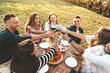 © Davide Angelini - Group of friends having fun at bbq outside dinner in home garden - Happy people cheering red wine sitting outdoor at dining table - Social gathering, youth, food and beverage concept