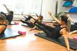 Diverse group of fit people in sportswear doing stretching together on a the floor of a gym during an exercise session