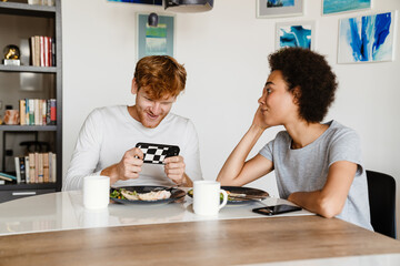 Wall Mural - Young disappointed african woman lookig at her smiling playing boyfriend