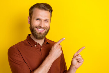 Canvas Print - Portrait of good mood handsome man with masculine beard wear burgundy shirt directing empty space isolated on yellow color background