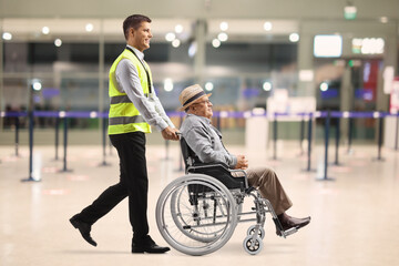 Poster - Full length profile shot of an airport worker pushing an elderly man in a wheelchair at the airport