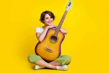 Sticker - Full size photo of lovely young girl folded legs guitarist music lover promo dressed stylish khaki look isolated on yellow color background