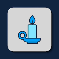 Poster - Filled outline Burning candle in candlestick icon isolated on blue background. Cylindrical candle stick with burning flame. Vector