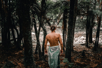 Canvas Print - caucasian boy with long hair tied back on his back with a towel covering his legs heading towards the river on waitawheta tramway, new zealand