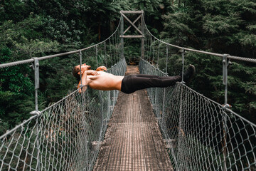 Canvas Print - naked caucasian young man pants shoes on top of an iron and wood bridge the trees of the forest on donut island, new zealand