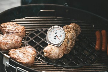 Poster - Closeup of delicious grilled meat on a grill with a thermometer