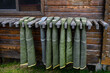 Collection of hip waders hanging up drying outside on a rustic wood cabin
