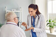 © Studio Romantic - Doctor talks about benefits and prescribes hearing aid to elderly man who has become hard of hearing. Friendly woman shows small comfortable digital or analog behind ear device to male pensioner.