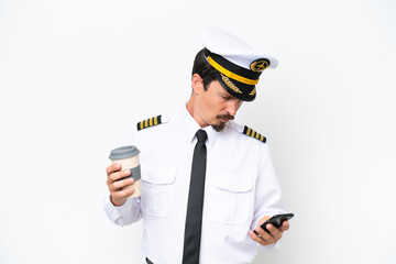 Canvas Print - Airplane caucasian pilot isolated on white background holding coffee to take away and a mobile