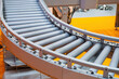 © Grispb - Conveyor for warehouse enterprise. Empty conveyor. Production line with gray rollers. Fragment conveyor for moving boxes. Equipment concepts for warehouse process automation. Bending production line