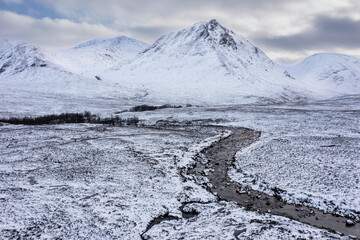 Wall Mural - Epic aerial drone landscape image of Stob Dearg and Glencoe in Scottish Highlands during deep snowfall and beautiful blue skies