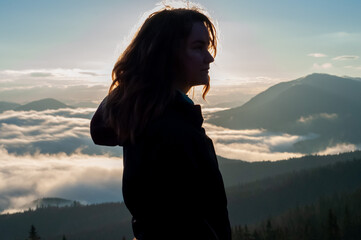 Wall Mural - portrait of a girl in the mountains above the clouds in the fog at dawn in the shadows silhouettes of the face peaks sunlight creations beauty of nature reflections meditation prayer