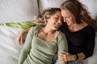 © Austockphoto - Female same sex couple  affectionately lying together on the bed