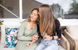 © Austockphoto - Lesbian couple on outdoor sofa, drinking wine and holding one another