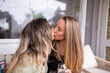 © Austockphoto - Same sex couple sitting on outdoor chair with wine, kissing