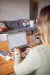 © Austockphoto - Close up shot of a woman typing on her laptop with cellphone, airpods, glass of water and mug