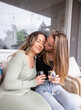 © Austockphoto - Same sex couple sitting on outdoor chair drinking wine and being affectionate