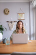 © Austockphoto - Woman wearing green sweater with eyeglasses working on laptop at kitchen table