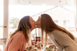 © Austockphoto - Female same sex couple kissing across the dining table at home