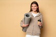 © Damir Khabirov - Fitness woman in sport hoodie holding plastic cup of coffee and rolled mat resting after training