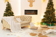 Two Xmas tree with lights glowing garlands and gifts. Festive interior design. Comfortable cozy living room interior with Christmas tree and sofa with pillows. Xmas at home. New year winter home decor