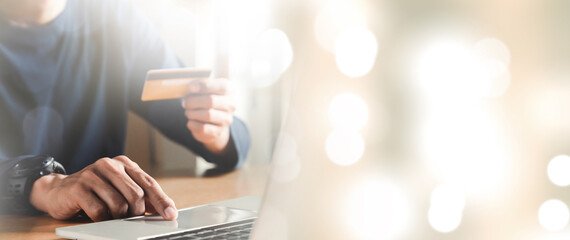 Man hand holding credit card and using laptop at home, Businessman or entrepreneur working, Online shopping, e-commerce, internet banking, spending money concept.