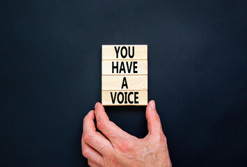 You have a voice symbol. Concept words You have a voice on wooden blocks. Beautiful black table black background. Businessman hand. Business, psychological you have a voice concept. Copy space.