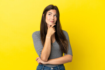 Wall Mural - Young Brazilian woman isolated on yellow background thinking an idea while looking up