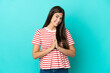 © luismolinero - Young Brazilian woman isolated on blue background keeps palm together. Person asks for something