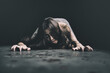 woman crawling on the floor, Halloween day horror concept. Asian woman zombie with blood creepy crawling Spooky ghost tousled hair covering her face with blood in hand reach out at night time.